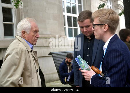 David Dimbleby, britischer Journalist und ehemaliger Moderator der Fragestunde Programm der BBC, vor dem Parteitag der Konservativen Partei, 2019 in Manchester, UK gesehen, interviewen zwei junge Männer. Stockfoto