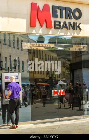 Bath, ENGLAND - JULI 2019: Person, die Geld von einer Geldpunktmaschine außerhalb einer Filiale der Metro Bank im Zentrum von Bath abzieht. Stockfoto