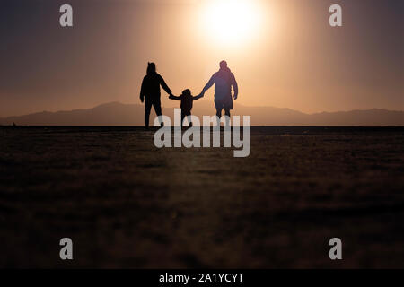 Familie silhouette halten sich an den Händen während einer schönen Sonnenuntergang auf alinas der Saline Grandes" in Jujuy, Argentinien Stockfoto