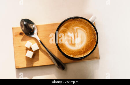 Tasse Latte Kaffee mit Schaum von oben, Löffel und Zucker auf weißem Hintergrund. Sonnigen Tag. Stockfoto
