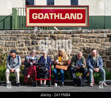 Die Reisenden und Schiene Enthusiasten saß auf Plattform Sitzbank, Goathland Station, North Yorkshire Moors Railway. Stockfoto