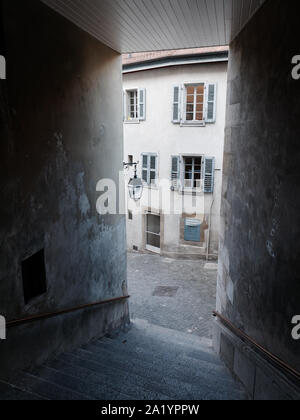 Mittelalterliche gepflasterte Strasse und ein altes Haus mit Fenstern mit Fensterläden aus Holz aus einer engen Gasse mit Treppen in der Altstadt von Genf, Schweiz, gesehen. Stockfoto