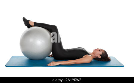 Gemischte Rasse Frau in den Vierzigern Pilates Training auf der Matte, mit einer Kugel isoliert auf weißem Stockfoto