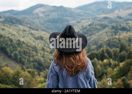 Ansicht der Rückseite des schöne junge Frau Abenteurer oder touristische liegt am Rand einer Klippe mit Blick auf den Herbst Berge. Reisen entdecken Sie echte Wildnis lifestyl Stockfoto