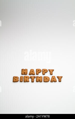 Die worte Happy Birthday durch braune Kekse gemacht auf die weiße Fläche im Hochformat Stockfoto