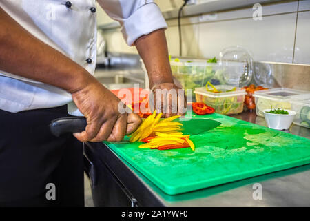 Afrikanische Koch Schneiden auf einem Brett gelbe und rote Paprika in der Küche Stockfoto