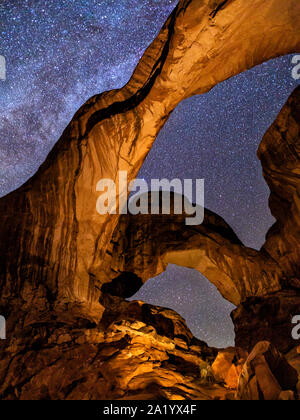 Der unnachahmliche Double Arch leuchtet von innen vor dem Hintergrund der Milchstraße im Arches National Park, Utah. Stockfoto