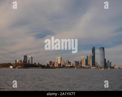 Der Jersey City, NJ Skyline entlang dem Hudson River mit Ellis Island. Das Wasser ist jetzt der Gold Coast Wegen der Sanierung genannt. Stockfoto