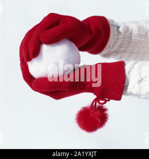 Die Frau Hände mit roten stricken Handschuhe holding Schneeball. Menschen, die Spaß im Schnee im Winter. Frauen kaltem Wetter Mode Accessoires. Stockfoto