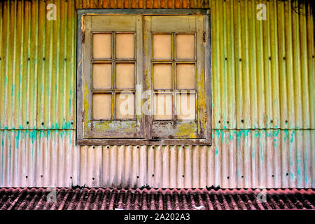 Antike Fenster mit braunen Fensterläden aus Holz auf Wellblech Äußere des Hauses in Geylang, Singapur Stockfoto