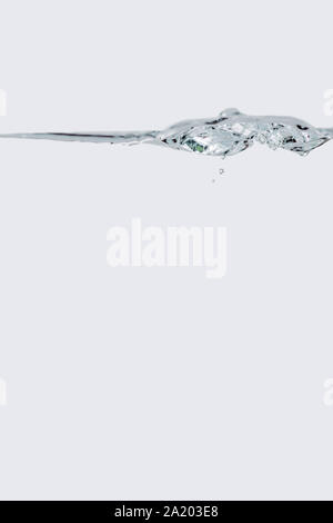 Nahaufnahme von einem kleinen Wasser Welle mit aufsteigenden Blasen vor weißem Hintergrund. Stockfoto
