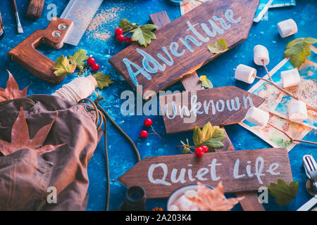 Schild mit Abenteuer, Unbekannte und ruhiges Leben. Travel Essentials kreativer Kopf mit Socken, Karten und Marshmallows, Fernweh Konzept Stockfoto