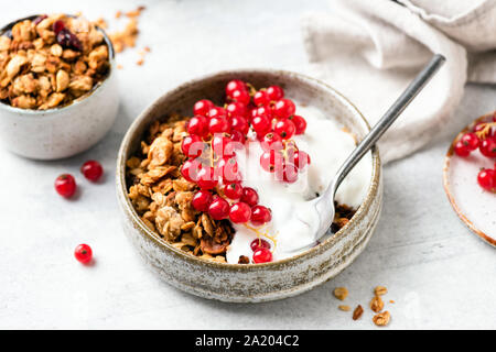 Leckeres Frühstück Müsli mit griechischem Joghurt und Beeren in der Schüssel auf grauem Beton Hintergrund. Vegetarische gesunde Frühstück Mahlzeit ausgeglichen Stockfoto