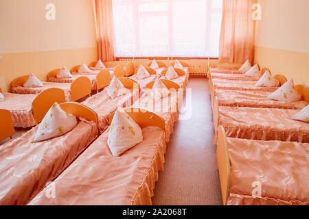 Zustell- und Kinderbetten sind in einem hellen Schlafsaal von einem Baumschule. eine Menge von Kinderbetten. Stockfoto