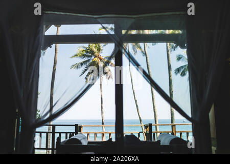 Tropische Ozean und Palm Tree View über die Villa Fenster in Bali. Freizeit und Ferien Konzept. Stockfoto