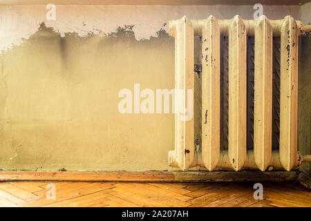 Alte gusseiserne Heizkörper mit abblätternde Farbe an der Wand Stockfoto