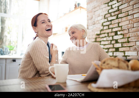 Rothaarige Betreuer lachen, während Rentner Witze Stockfoto