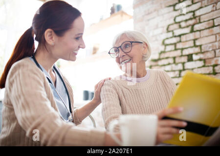 Rothaarigen Krankenschwester lächelnd, während im Gespräch mit Art gealterte Frau Stockfoto