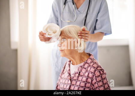 Grauhaarige Frau mit starken Kopfschmerzen Stockfoto