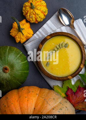 Vegetarisch Herbst Kürbis creme Suppe in Houten mit Samen, Farbe Laub, Kürbisse, Nahaufnahme Stockfoto