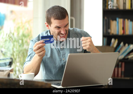 Zornigen Mann Probleme online mit Kreditkarte in einem Café sitzen zu zahlen Stockfoto