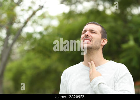 Der Mensch leiden Hals Schmerzen klagen allein in einem Park Stockfoto