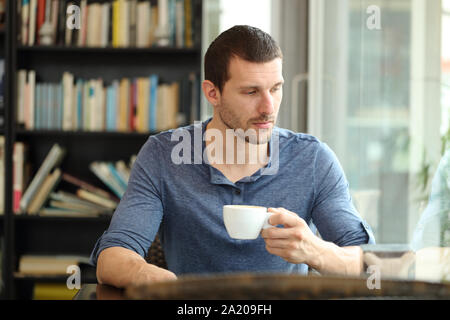 Nachdenklicher Mann traurig schaut weg durch ein Fenster in ein Café oder nach Hause Stockfoto