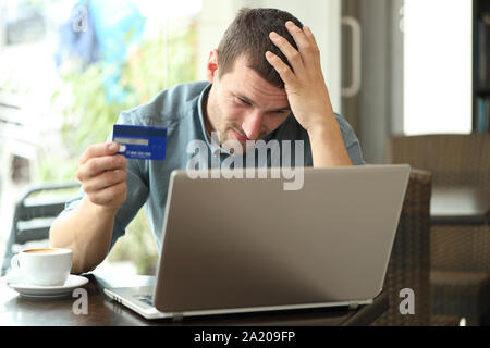 Besorgt man Probleme bei der Zahlung mit Kreditkarte und Laptop in einem Café sitzen Stockfoto