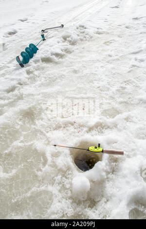 Im Winter Angeln liegen auf dem Eis in der Nähe der Bohrung und liegt neben der Borer Stockfoto