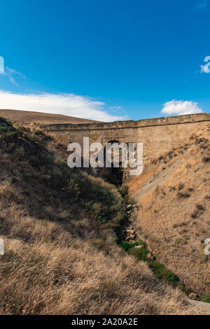 Alten baufälligen steinernen Brücke über einen kleinen Fluss Stockfoto