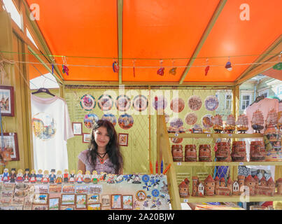 Porträt der Schönen lächelnden jungen Frau Krämer Kasitoo Handarbeit Open-Air-Markt Tallinn, Estland mit Souvenirs. Europäische Reise & Tourismus Stockfoto