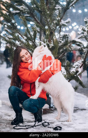 Eine Frau umarmt ihren Hund auf einer Nacht Straße. Stockfoto