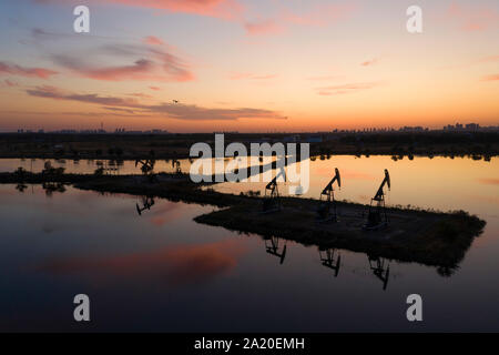 (190930) - DAQING, Sept. 30, 2019 (Xinhua) - Luftaufnahme auf Sept. 27, 2019 zeigt sunset Landschaft in Daqing Oilfield in Daqing im Nordosten der chinesischen Provinz Heilongjiang. Daqing Oilfield, Sept. 26, 1959 entdeckt, ist das größte ölfeld von PetroChina und auch das größte Öl Produktionsbasis. Das Ölfeld, einmal die über die Hälfte des Chinesischen insgesamt ausgegeben, Rohöl Rohöl hatte eine jährliche Produktion von über 50 Millionen Tonnen für 27 Jahre und mehr als 40 Millionen Tonnen für 12 gerade Jahre. Seine jährliche Rohöl und Gas Ausgang bleibt immer noch über 40 Millionen Tonnen Stockfoto