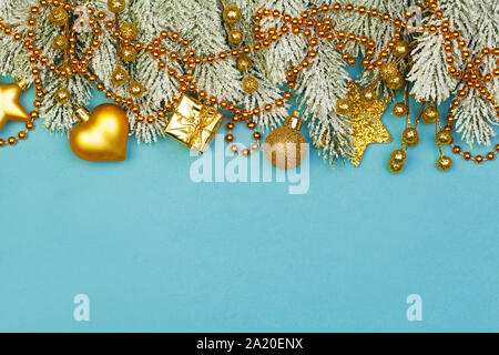 Bunte Weihnachten Grenze Hintergrund. Weihnachten Urlaub Komposition mit gold Garland, Beeren, Geschenke und Grüne Tanne Zweig auf blauem Hintergrund Stockfoto
