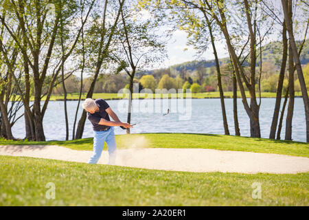 Ältere Golfspieler spielen vom Bunker. Stockfoto