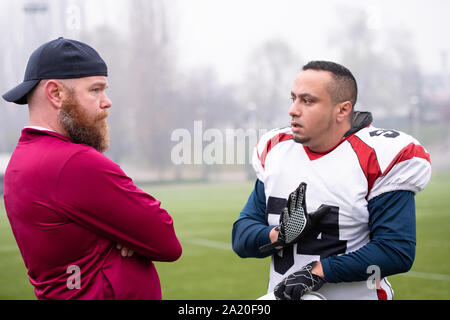 Young Professional football player diskutieren Strategie gemeinsam mit Trainer während der Ausbildung übereinstimmen, der auf dem Stadion Feld Stockfoto