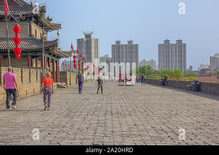 Editorial: XI'AN, Shaanxi, China, April 11, 2019 - Touristen zu Fuß auf der Stadtmauer von Xi'an mit modernen Gebäude auf der rechten Seite Stockfoto