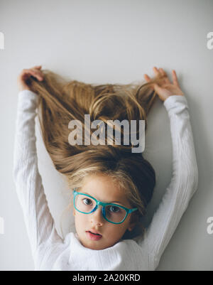 Schöne kleine kaukasische Mädchen in Blau Brille ihre langen blonden Haare, die bis Stockfoto