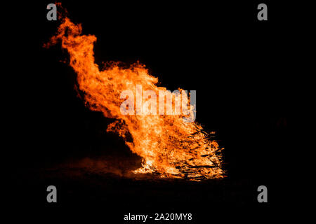 Großes Lagerfeuer aus Holz auf einem schwarzen Hintergrund. Zungen der Flamme gegen den Nachthimmel. Stockfoto