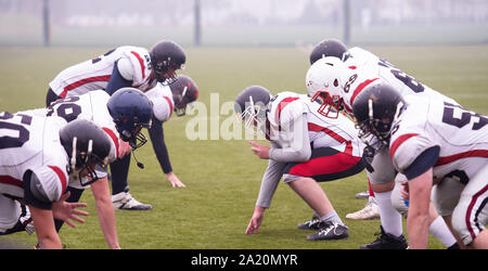 Gruppe von jungen professionellen American Football Spieler bereit während der Ausbildung übereinstimmen, der auf dem Stadion Feld beginnen Stockfoto