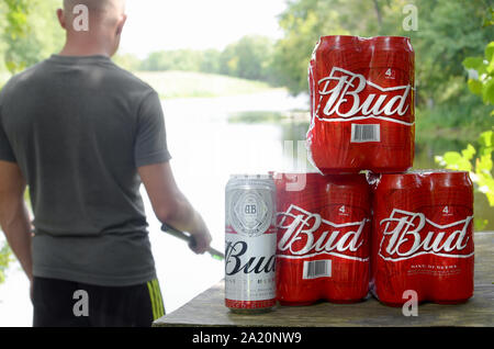 Kharkov, Ukraine - August 10, 2019: Budweiser Bud Bierdosen pack auf alten Tisch und Fischer am Fluss für den Hintergrund. Budweiser ist einer der beliebtesten Stockfoto