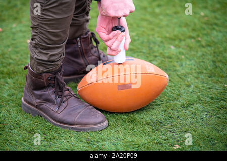 Nahaufnahme der Mann auf dem Feld pumpt Luft in eine Professionelle ball für American Football Stockfoto