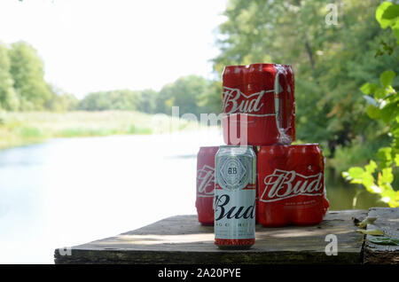 Kharkov, Ukraine - August 10, 2019: Budweiser Bud Bier kann auf alten hölzernen Tisch draußen am Fluss und grüne Bäume Hintergrund. Budweiser ist einer der Stockfoto