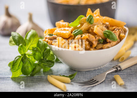 Pasta Penne mit Huhn Stücke Pilze Basilikum und Parmesan italienische Küche in weiße Schüssel am Küchentisch Stockfoto