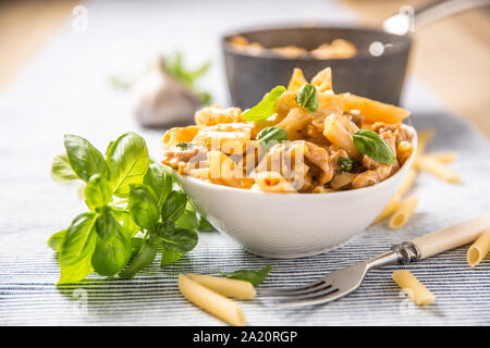 Pasta Penne mit Huhn Stücke Pilze Basilikum und Parmesan italienische Küche in weiße Schüssel am Küchentisch Stockfoto