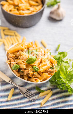 Pasta Penne mit Huhn Stücke Pilze Basilikum und Parmesan italienische Küche in weiße Schüssel am Küchentisch Stockfoto