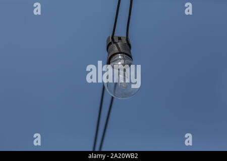 Blick auf eine alte Glühlampe, Kabel, draußen auf der Straße mit blauer Himmel... Stockfoto