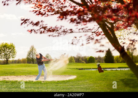 Männliche Golfspieler, der aus dem Sandbunker dar. Stockfoto