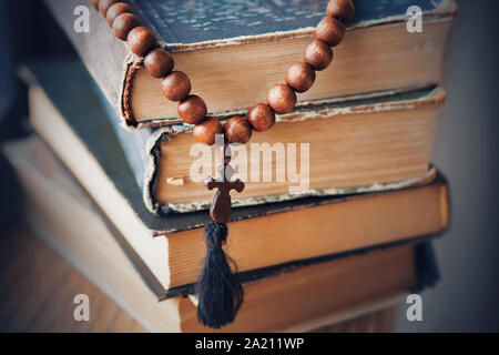 Der heilige Rosenkranz, aus Mahagoni, liegt auf einem Stapel der alten zerschlagenen Bücher, in denen die religiösen Gebote geschrieben sind. Stockfoto