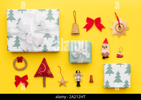 Verpackte Weihnachtsgeschenke und viele retro Weihnachten Ornamente auf gelben Hintergrund. Weihnachten Komposition. Stockfoto